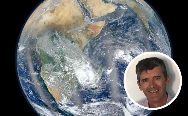 El geofísico Manuel Catalán, junto con una imagen del planeta Tierra./IDEAL